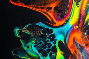 colorful mix of neon paints swirling on black surface